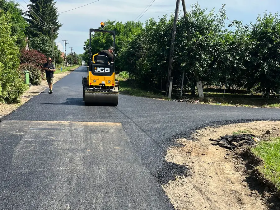 JCB tandem henger tömöríti a friss aszfaltot kertek közötti keskeny behajtón