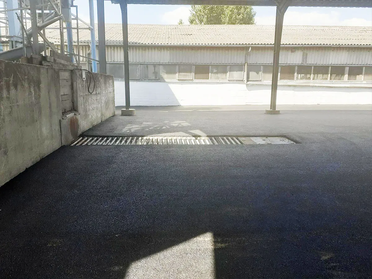 Aszfaltozott udvar ipari csarnok előtetője alatt, beépített vízelvezető rács